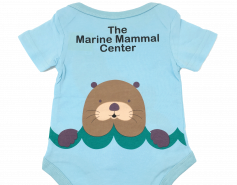 blue short-sleeved onesie with cartoon sea otter face and the words The Marine Mammal Center