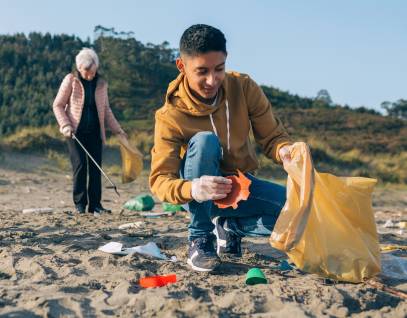 a young man and older woman conducting a beach cleanup