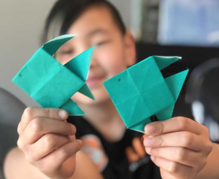 student showing off a fish origami project