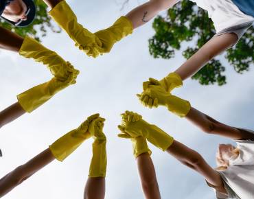 circle of young people wearing work gloves and holding hands