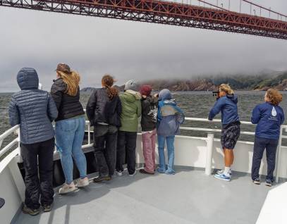 young people on a boat traveling under the Golden Gate Bridge