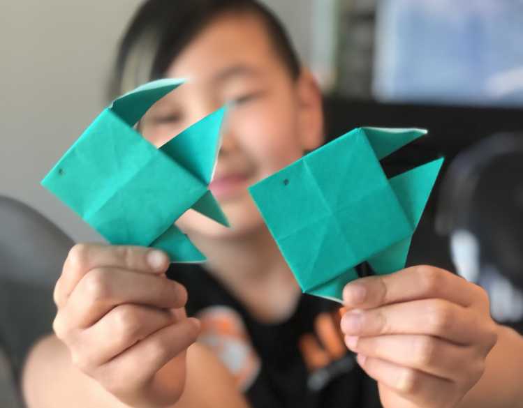 student holding up fish-shaped origami